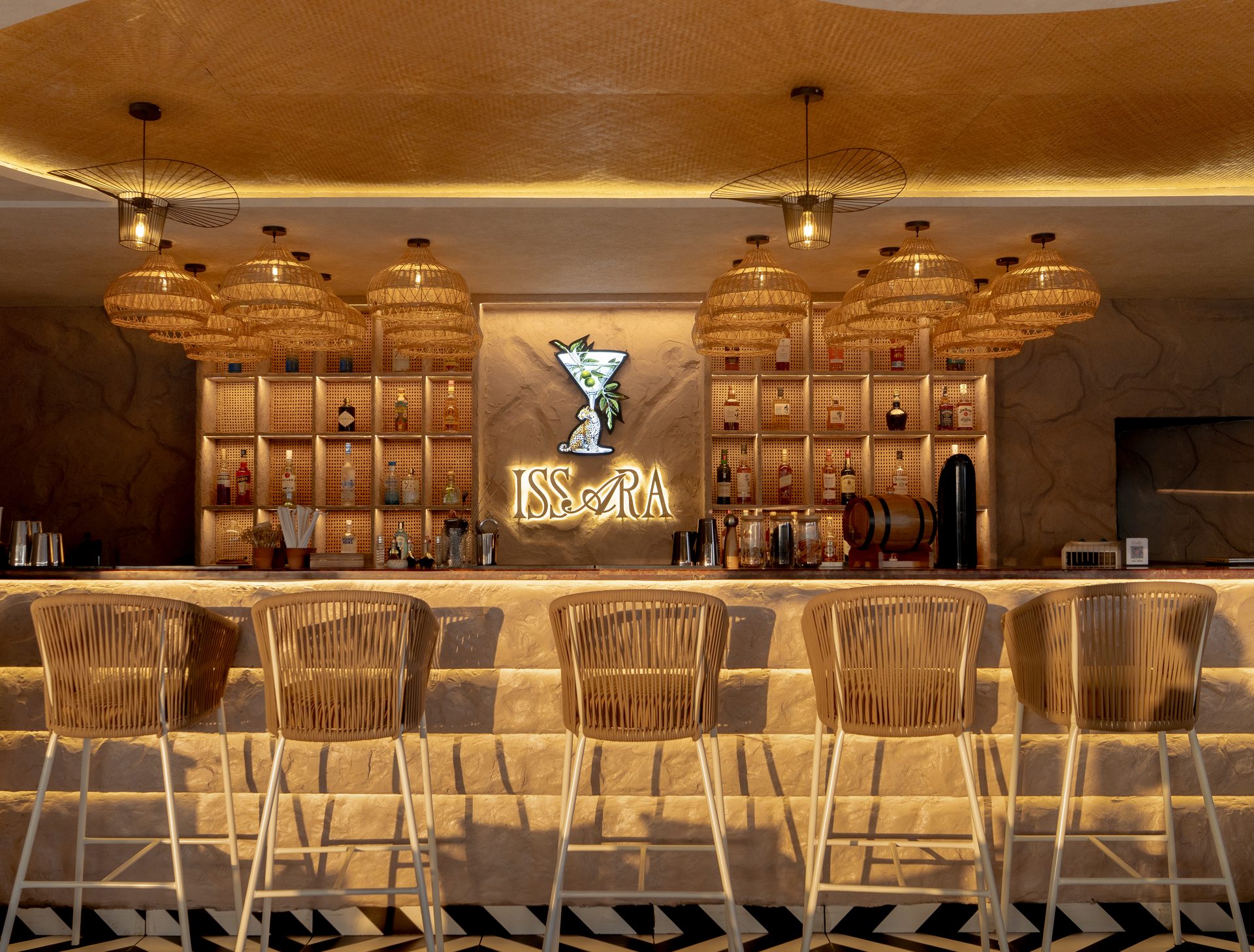 Issara Main Bar Counter with cane chairs and backlit bottles